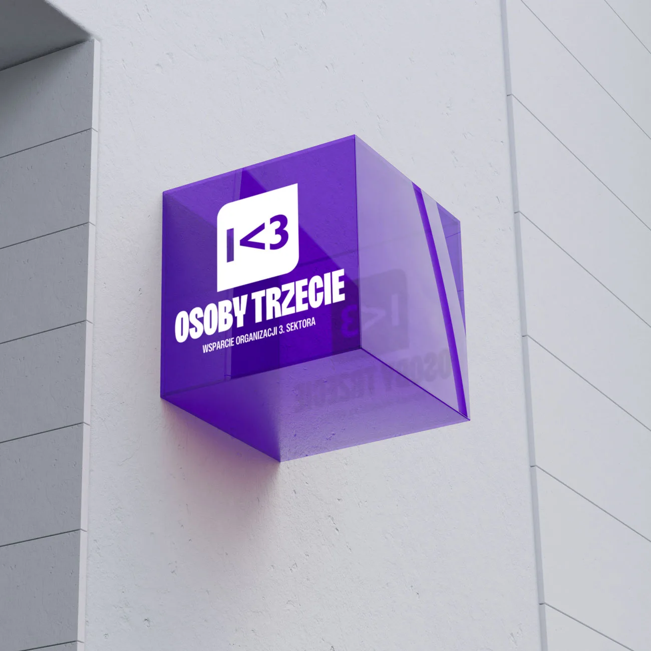 Purple translucent cube sign mounted on a white wall with text and a heart symbol.